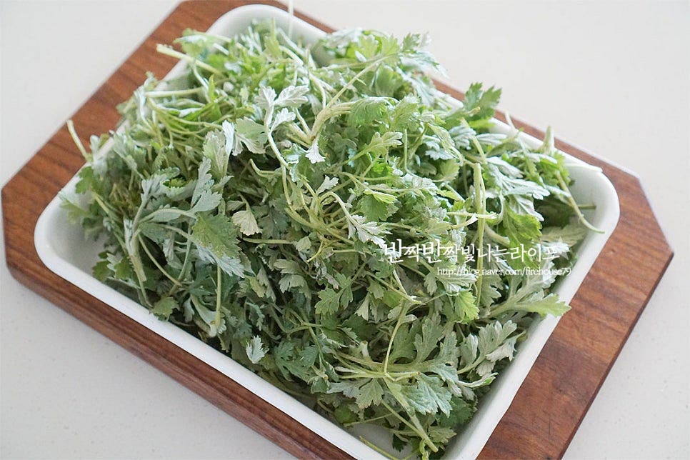 봄을 알리는 향긋함 요즘 한창 쑥이 많이 보이죠~ 그대로 올려놓기만 해도 향이 진해요. 먼저 억센 줄기나 상한 잎은 다듬어 정돈해 줍니다. 흙이 사이사이 많이 묻어나기 때문에 꼼꼼하게 세척하여 주는 것이 중요해요. 잠길 정도로 물을 부어 살살 흔들어 씻어주고, 상태에 따라 흙이 많이 나온다면 잠시 물에 담갔다 흔들어주시면 더 잘 씻깁니다. 여러 번 흔들어 꼼꼼하게 씻어준 뒤 체에 밭쳐 물기를 털어줍니다. 이때 완전히 수분을 제거하지 않고 가볍게 털어주면 수분이 어느 정도 촉촉한데요. 그럼 나중에 가루와 더 잘 어우러져요.