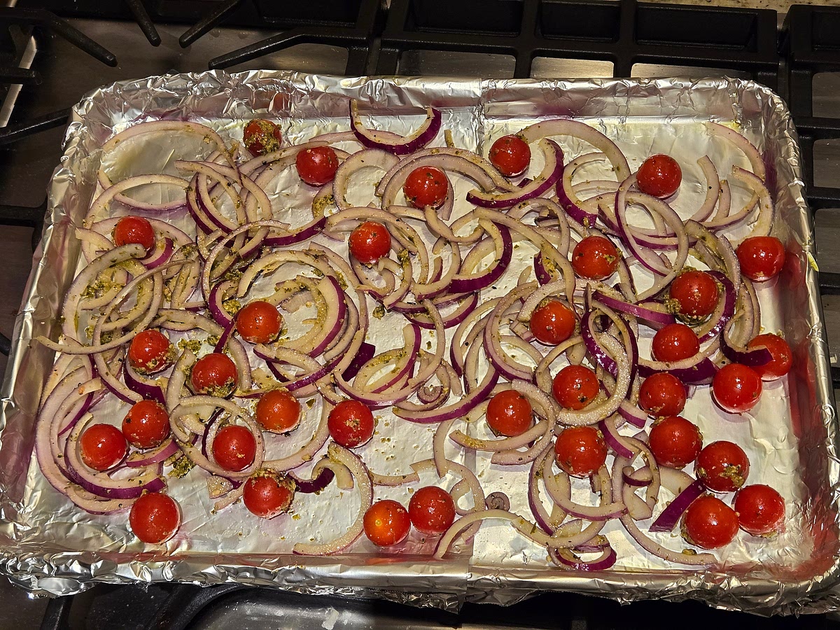 Place the cherry tomatoes and red onion in a large bowl. Add 2 tablespoons pesto, 1/4 teaspoon kosher salt, and ¼ teaspoon black pepper. Toss to coat, then spread into a single layer on the prepared baking sheet.