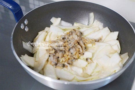 바지락살과 맛술 1/2 큰 술을 넣어줍니다. 냉동된 것이라 질기지 않게 그대로 넣어주고, 비린내가 나지 않게 맛술을 더했습니다. 생물은 먼저 볶은 뒤 박을 넣어주셔도 됩니다. 조갯살과 볶아지면서 수분이 촉촉해집니다. 간 마늘 2/3 큰 술, 멸치 다시마 육수 또는 물(쌀뜨물)을 넣어줍니다. 육수나 물의 양은 화력에 따라 자작하게 조절해 주세요. 뚜껑을 덮고 3분 정도 익힌 뒤 뚜껑을 열어보면 투명 빛이 나면서 국물도 자박자박합니다. 두께에 따라 익는 시간은 다르므로 그에 맞게 조절하여 뭉근히 익혀주세요. 부족한 간은 소금으로 조절하고 들깨가루나 통깨를 곁들여 마무리합니다. 국물과 같이 떠서 먹는 맛이 있는 박나물은 촉촉하게 만들면 더 맛이 좋습니다.