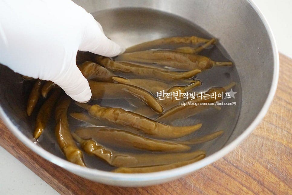 소금에 절인 고추지는 물에 살살 흔들어 씻어 소금기를 빼줍니다. 안에 스며든 소금물도 빼주기 위해 끝부분을 약간 자르거나 이쑤시개로 콕 찔러 흔들어 씻어주시면 됩니다. 소금기를 제거하여 준 뒤 키친타월로 살살 눌러가며 물기를 제거하여 줍니다.