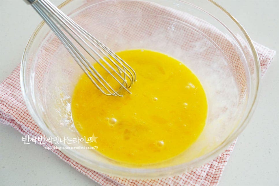 넉넉한 크기의 볼에 계란 2개와 노른자 1개를 넣고 가볍게 풀어줍니다. 설탕 60g, 꿀 12g 소금 한 꼬집, 바닐라익스트랙 1g을 넣어줍니다. 꿀이나 물엿이 들어가면 더욱 촉촉하게 만들 수 있습니다. 뜨거울 물이 담긴 냄비 위에 믹싱볼을 올려줍니다. 거품기로 재료가 섞이도록 풀어줍니다. 뜨거운 물 위에서 젓다 보면 계란물의 온도가 40도 정도의 따뜻한 상태가 됩니다. 그럼 볼을 꺼내어 내려놓습니다.