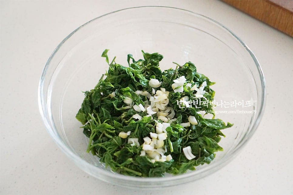 넉넉한 크기의 볼에 데친 오가피순과 다진대파 1 큰 술을 넣어줍니다. 국간장 1/3 큰 술, 참치액 1/2 큰 술 간 마늘 1 작은 술, 매실액 1 작은 술 참기름 1 큰 술을 넣어줍니다. 참치액과 국간장을 섞어 넣어 짭조름한 감칠맛을 더해주었는데요. 간에 따라 짠맛을 조절해 넣어주세요.