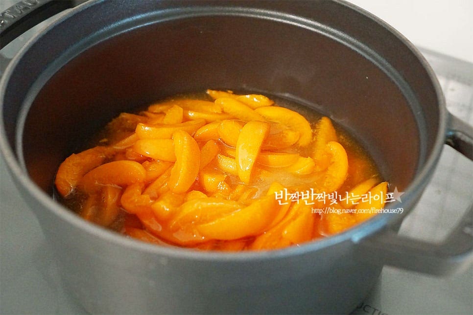 설탕이 녹으면 냄비에 담아줍니다. 중불로 끓여줍니다. 끓이다 보면 거품이 생기는데요. 거품을 제거해 주시면 보다 깔끔하게 만드실 수 있어요. 10~15분 정도 끓이니 과육이 잘 익었어요. 불을 끄고 과육을 핸드블렌더로 갈아줍니다. 씹히는 식감이 있게 만드시려면 갈지 않으셔도 됩니다. 블렌더로 갈아준 뒤 다시 중불로 끓이면 주황색이 더 짙어지는데요. 그럼 레몬즙 1 큰 술 넣어줍니다. 레몬즙은 풍미를 살려주며 오래 두고 보관할 수 있게 도와주는 역할을 해요. 약불로 눌어붙지 않게 계속 저어가며 농도를 맞추어줍니다. 과육을 부드럽게 갈아 끓이면 용암처럼 끓어오르기 때문에 뜨거움에 주의하며 계속 저어줍니다. 묽은 듯 보이지만 식으면 그렇지 않아 농도를 맞추어 주는 것도 포인트에요. 찬물에 조금 덜어 떨어뜨려보았을 때 퍼지지 않고 아래 사진과 같이 그대로 모양이 유지되면 농도가 적당히 된 것이에요.