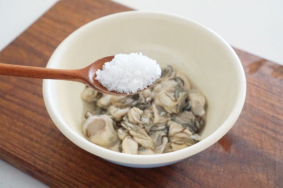 굴을 깨끗하게 씻어줍니다. 굵은소금 1 큰 술 정도를 넣고 살살 흔들어가며 씻어줍니다. 터지지 않게 살살 씻어주고 흔들어 씻다 보면 이물질이 나와 검은빛이 돌아요. 흐르는 물에 살살 씻어 물기를 털어줍니다. 중간중간 혹시 껍질이 있다면 제거해 주시고요.