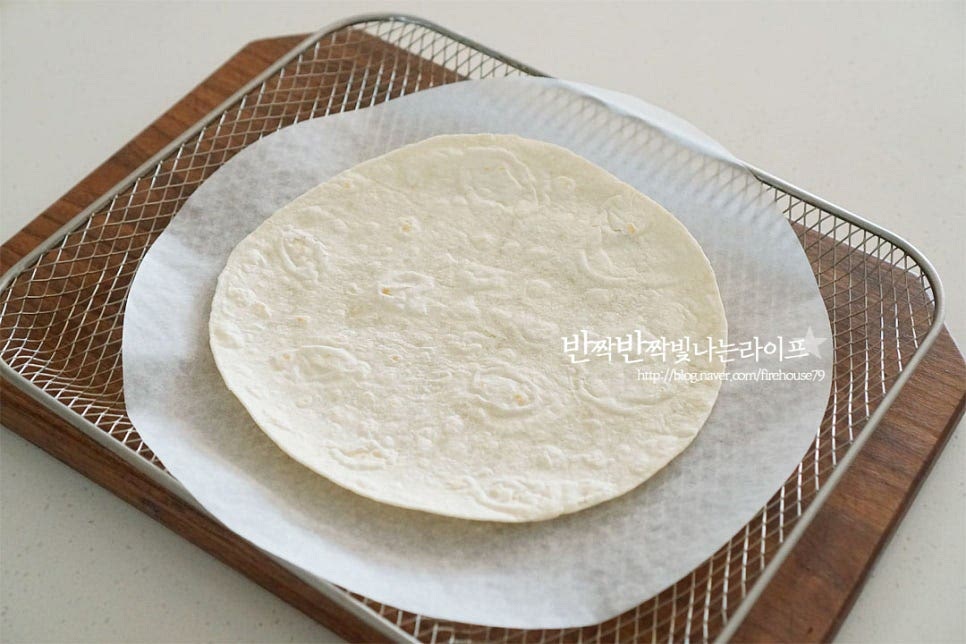 바스켓에 종이호일을 깔고 또띠아를 올려줍니다. 간편하게 에프를 사용하였는데 오븐에 구워주셔도 좋습니다. 그 위로 소스를 얇게 펴서 발라줍니다. 얇게 펴서 발라주면 식감이 더 바삭하고 조금 두툼하게 발라지면 바삭+쫀득한 식감입니다. 식감을 살려 굽고 한입에 집어먹기 좋도록 가위로 일정한 크기로 잘라줍니다. 동그란 모양이라 피자처럼 잘라주었는데 길게 잘라주셔도 좋고 모양은 자유롭게 준비해 주세요.