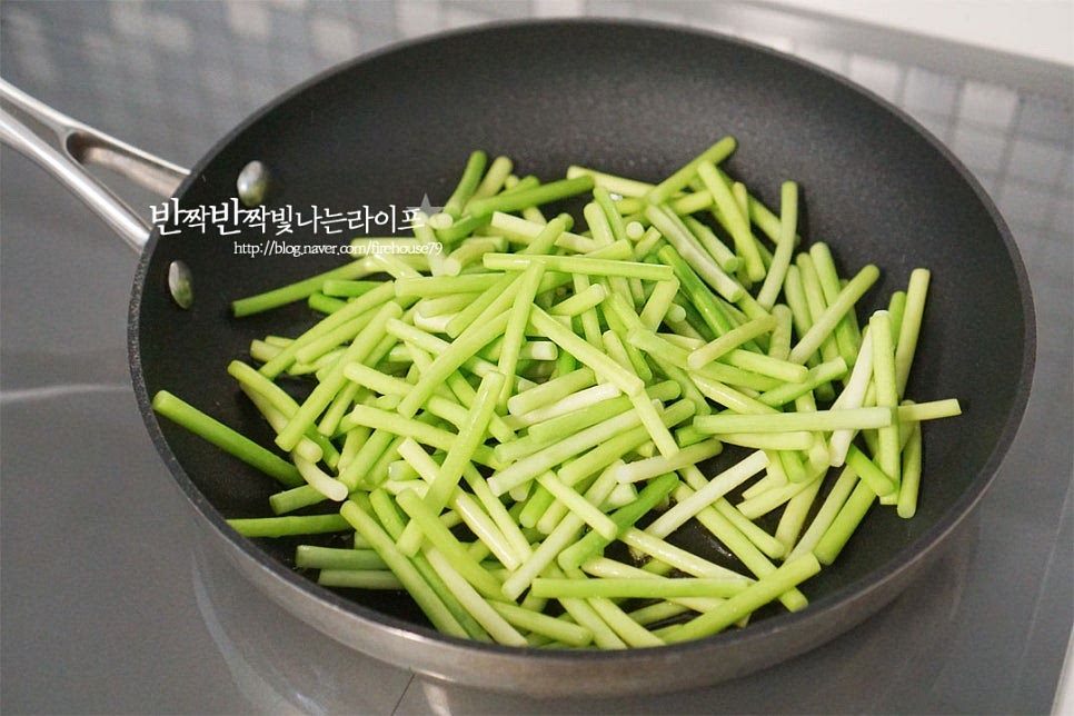 달군 팬에 식용유 1 큰 술 두르고 데친 마늘쫑을 넣고 전체적으로 기름이 코팅되도록 볶아줍니다. 1분 정도 가볍게 볶다가 만들어둔 양념소스를 넣어줍니다. 양념이 밸 수 있도록 중불에서 볶아가며 수분을 날려줍니다. 졸이듯이 볶다 보면 색이 진해지고 점점 더 진해집니다. 양념이 쏙 배어들면 건새우를 넣고 함께 볶아줍니다. 마른 새우는 양념이 흥건할 때 넣으면 식감도 눅눅해지고 간장양념에 짜게 될 수 있어 마늘쫑에 간이 배면 넣어주세요. 서로 어우러지도록 볶아줍니다. 참기름 1 큰 술, 통깨 약간 뿌려 마무리해요.