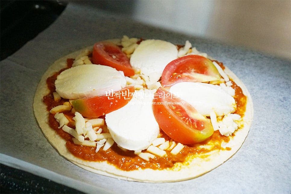 200도 예열한 오븐에 넣고 8~10분 구워줍니다. 에어프라이어 같은 경우 180도 8~10분 구워주면 되어요. 기기의 사양에 따라 시간은 가감해 주세요. 또띠아피자만들기 할 때 오븐이나 에프가 없다면 예열한 프라이팬 위에 올려 약불로 뚜껑을 덮고 치즈가 녹게 구워주셔도 좋습니다. 저는 8분 구워주니 도우가 바삭하고 속 재료가 잘 익었어요. 원래라면 화덕에 구워 맛을 내야 하지만 얇은 필랫브레드인 또띠아 피자를 만들면 특유의 담백 고소한 맛을 살릴 수 있어요. 마지막으로 바질잎을 올려 마무리해요. 바질을 올리면 색감은 물론 향긋함이 더해져 맛이 좋아요~ 집에서 피자 만들기 도우 대신 담백한 또띠아 위에 모짜렐라치즈, 토마토, 바질을 토핑 하면 근사하고 맛있는 마르게리따 피자가 완성되어요. 갓 구웠을 때 먹음 담백 고소하면서 산뜻한 맛이 별미랍니다. 영상도 같이 담았어요. 다양한 재료를 넣어 만들 수 있는 피자 중에서도 마르게리타피자의 매력은 기본적인 밸런스가 조화롭다는 것이에요. 재료, 조리과정이 간단하며 집에서 누구나 쉽게 만들 수 있는 레시피이니 간식이나 한 끼 식사, 별미로 만들어 보시는 것도 좋을 것 같아요. 마르게리타 피자 만들기 맛있게 요리해 드세요^^ 끄읕 !