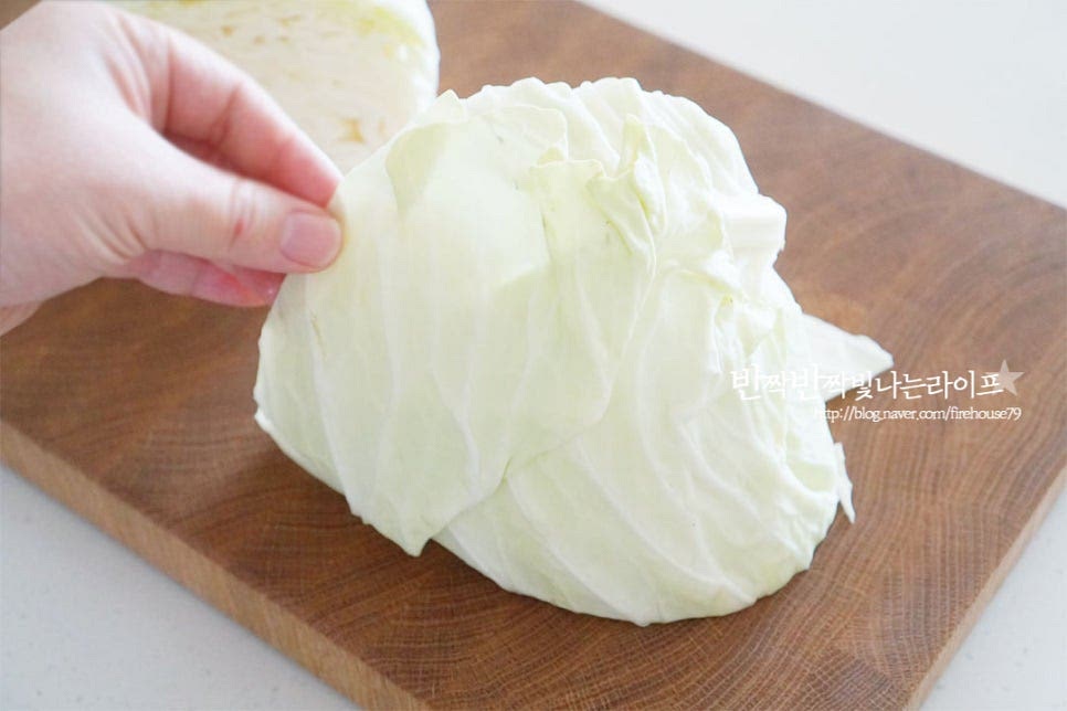 양배추 1/2통을 2등분으로 나누어 준비했습니다. 겉의 시든 잎은 뜯어내어주고 세척 후 먹기 좋게 물에 삶는법과 찜기로 찌는법을 알려드리려고 해요. 들어보았을 때 속이 꽉 차서 묵직한 것이 맛이 좋으며 겉껍질은 초록빛이 선명한 것이 좋습니다. 가운데 단단한 심지 부분은 대각선 방향으로 칼을 넣고 잘라내어줍니다.
