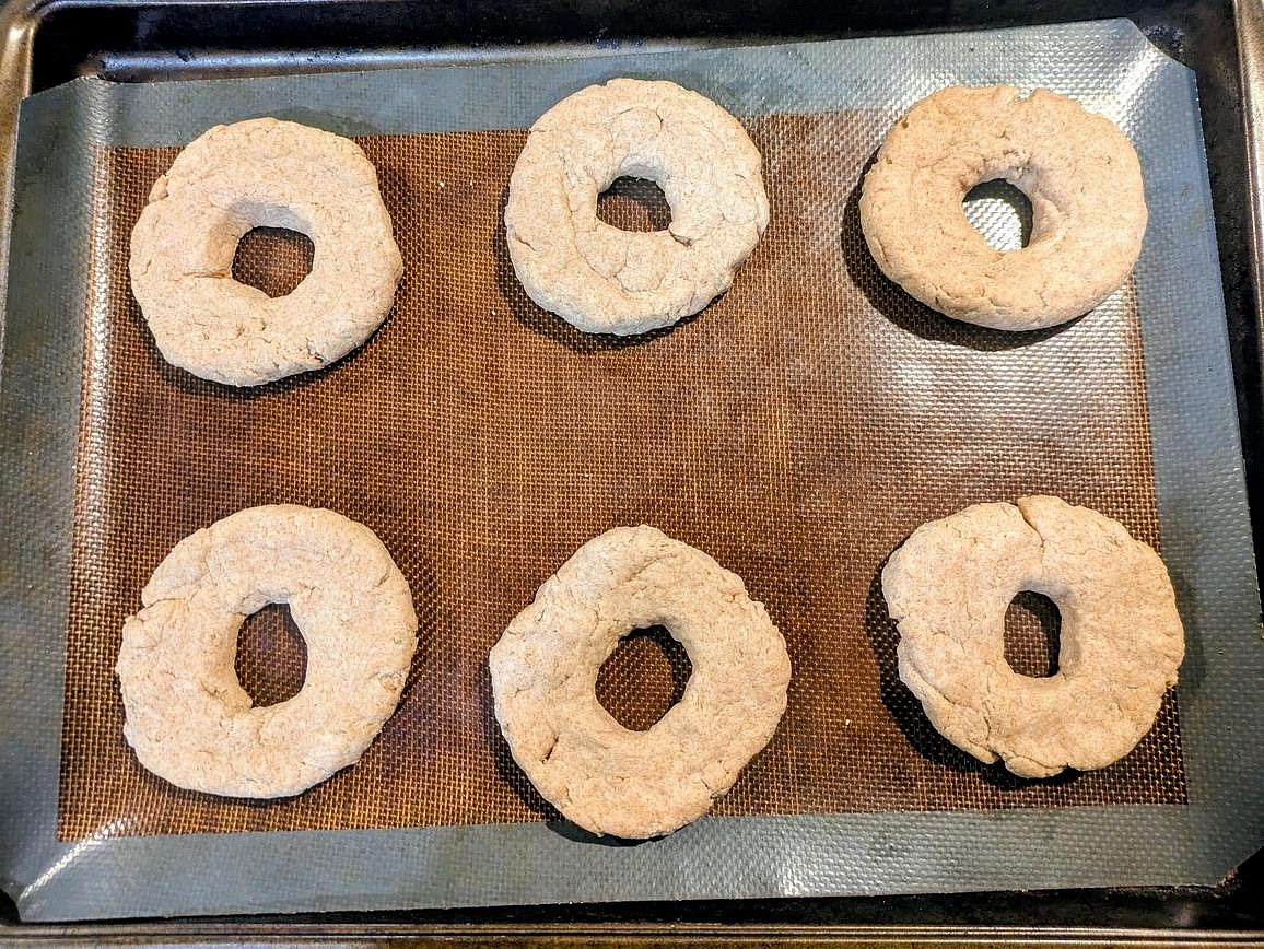 Use your fingers to carve out a hole in each piece, and shape into a round and flat bagel. Add to the baking tray. They won't expand outward as they bake, but they will puff up slightly