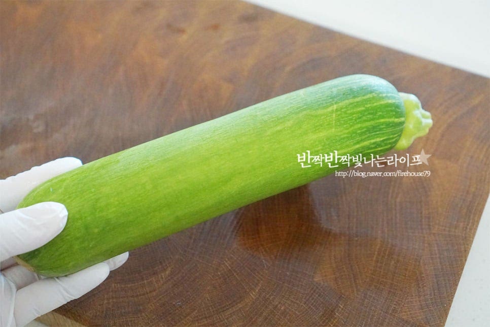 애호박 1개를 준비했습니다. 포장된 비닐을 제거하고 깨끗하게 세척 후 물기를 제거해 줍니다. 양 끝 부분은 잘라내고 길게 반으로 가른 뒤 0.5~0.7cm 두께로 일정하게 반달 모양으로 잘라줍니다. 일정한 두께로 썰어야 골고루 익어 무르거나 부서지지 않습니다.