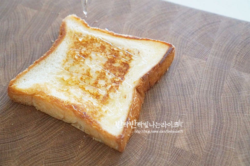 빵 위에 꿀 1 큰 술을 골고루 뿌려줍니다. 꿀 대신 연유도 좋습니다. 달콤한 시럽이 들어가면 달달하고 고소하게 어울려요. 양은 좋아하는 정도에 맞게 조절하여 주세요. 그 위로 자른 인절미 떡을 올려줍니다. 크기에 따라 겹치지 않게 토핑 해주면 된답니다. 떡 위로 꿀 1 큰 술을 뿌려줍니다. 양은 조절하되 골고루 뿌려주어야 단맛이 조화롭게 어우러진답니다. 빵으로 덮어줍니다. 햄이나 치즈, 계란 같은 속 재료를 넣는 것 대신 인절미와 꿀을 넣어 식감과 풍미를 살려주어요.