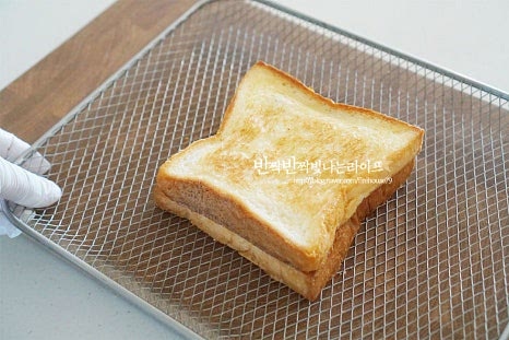 트레이에 올려 줍니다. 전자레인지나 프라이팬에 구워도 좋지만 에프에 구워 요리하면 겉의 식감이 더 바삭하고 고소하고 속까지 쫀득하게 잘 구워져 맛나더라고요. 에어프라이어 180도 5분 기준으로 2~3분 시간을 조절하여 구워줍니다. 저는 한번 구워준 것이라 겉이 타지 않게 바삭하도록 5분에 2분 더 구워주었습니다. 기기의 사양에 따라 온도와 시간은 조절해 주고, 중간에 한번 뒤집어주면 속까지 골고루 익어요. 인절미 에어프라이어 요리할 때 쫄깃한 떡이 뜨겁게 조리되면서 쫀득하게 어우러져 마치 치즈같이 쭉 늘어나는 맛이 된답니다. 속까지 따뜻하게 구워지면 완성입니다. 먹기 좋게 4등분으로 잘라줍니다. 네모, 세모 모양은 다양하게 썰어주세요. 그 위로 볶은 콩가루와 아몬드 슬라이스를 올려줍니다. 단맛에 따라 연유 약간 곁들여주면 프랜차이즈에서 먹던 맛이 난답니다. 식빵 사이로 인절미와 꿀을 넣고 겉은 바삭하고 고소하게, 속은 쫀득쫀득 달콤하게 요리하면 겨울철 별미 간식이 따로 없는데요. 친근한 인절미떡의 구수한 맛이 빵과 어우러져 더욱 맛이 좋답니다. 영상도 같이 담았어요. 뜨거울 때 바로 먹어야 본연의 식감을 제대로 맛볼 수 있는데요. 속에 든 인절미가 쭈욱 늘어나는 맛이 치즈 못지않게 맛이 좋습니다. 고소한 콩가루와 아몬드까지 풍부한 맛을 한 번에 느낄 수 있으며 친근하고 아는 맛이라 더욱 맛나요. 에어프라이어로 간단하게 만드는 인절미 토스트 만들기 바삭 고소 달콤한 맛을 맛있게 즐겨보세요. 끄읕 !