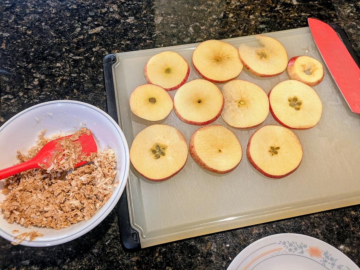 In a small bowl, mix together coconut flakes, almond butter, and honey until you have a fully combined dough. Place a thin and even layer of the coconut mixture on top of each apple slice