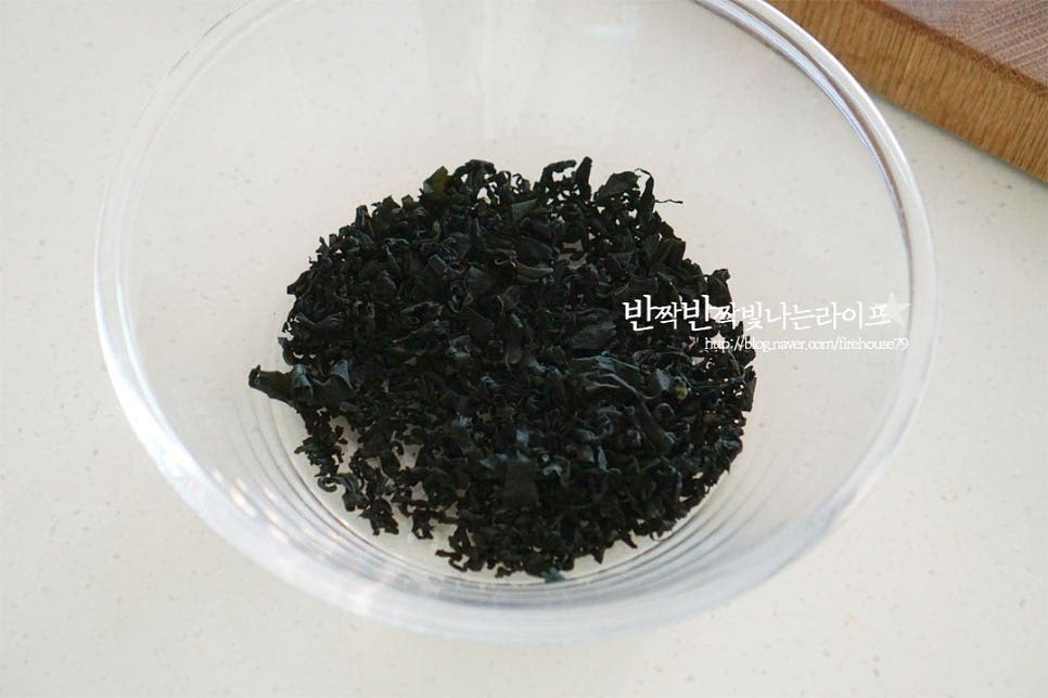 마른 미역은 자른 것으로 20g 정도 준비했습니다. 건더기를 푸짐하게 먹고 싶다면 5~6g 정도 더 넣으셔도 됩니다. 양이 적어 보이지만 불리면 부피가 늘어나니 적당량을 준비하는 것이 좋습니다. 믹싱볼에 넣고 물을 잠길 정도로 부어줍니다. 자른 미역이라 요리하기 좋아 불리는 시간도 적고 손질이 편합니다. 자연산은 이물질이 많이 나오기 때문에 꼼꼼하게 세척해 주셔야 합니다. 비린내가 나지 않게 찬물을 부어 10~20분 정도 불리면 보드랍게 불어납니다. 불리면 살짝 흔들어가며 세척한 뒤 채반에 밭쳐 물기를 털어 준비해둡니다. 길이에 따라 먹기 좋게 가위를 사용해 자르거나 칼로 썰어주세요.