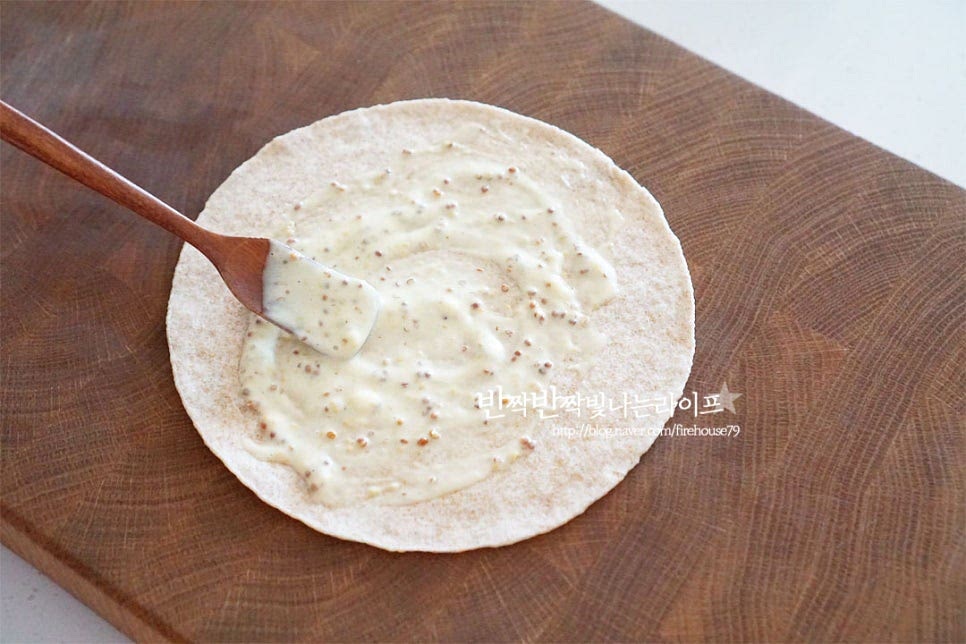 구운 재료 위에 소스를 발라줍니다. 그 위로 로메인을 깔고 파프리카와 토마토를 올려줍니다. 슈레드치즈를 뿌리고 치킨텐더를 올려줍니다. 치킨은 크기에 따라 양을 조절해주세요. 양끝을 접어 말아줍니다. 속을 가득 채워서 먹는 식감을 좋아해서 가득 넣고 샌드위치를 만들었습니다. 랩으로 돌돌 말아 모양을 고정해 줍니다. 치킨랩을 감싸면 손에 쥐고 먹기 편합니다. 반으로 잘라줍니다. 단면이 보이면 속재료 가득 맛있어 보인답니다.