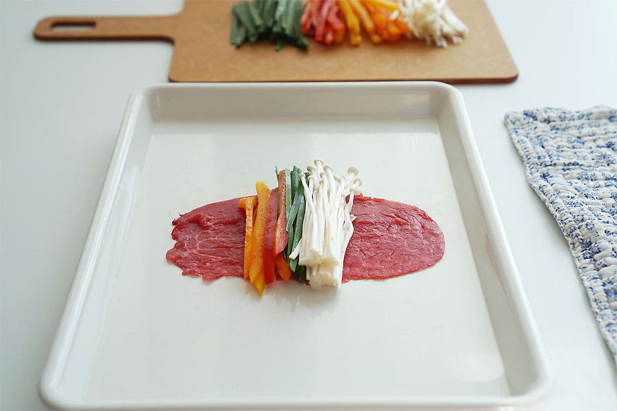 재료를 돌돌 말아요. 밑간 한 고기를 펼치고 그 위로 손질해둔 채소를 종류별로 조금씩 올려준 뒤 돌돌 말아주면 되어요. 얇게 저민 고기라서 잘 말리는데 이음새 부분을 고정해 주고 싶다면 전분가루를 조금 묻혀 말아주세요.