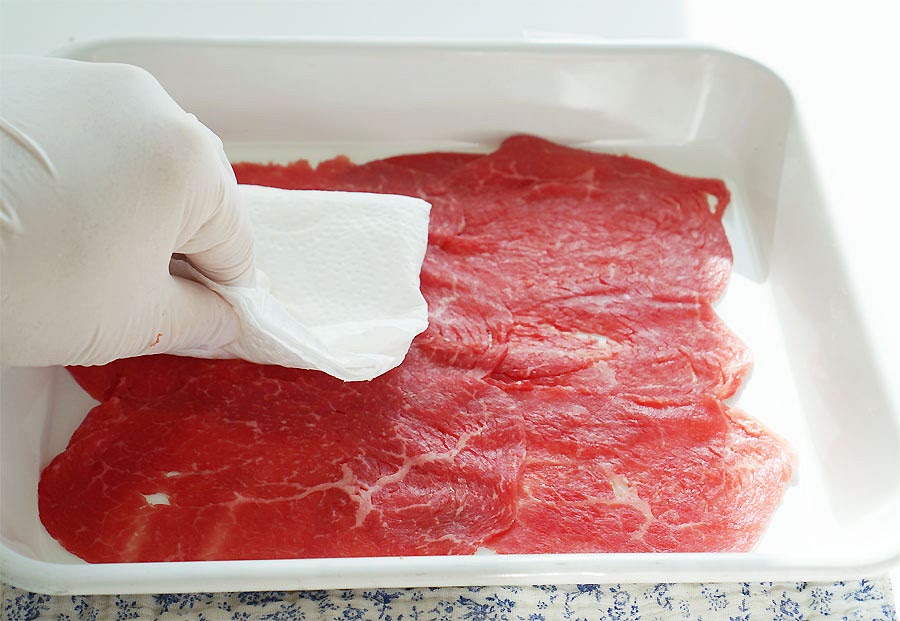 고기 밑간을 해주세요. 불고기용 고기로 얇게 저민 걸 준비했어요. 먼저 키친타월로 핏물을 닦아내어 줍니다. 맛간장 1, 맛술 1, 참기름 1을 섞은 뒤 솔을 이용하여 골고루 발라주세요. 간을 간간하게 하고 싶다면 간장 양을 늘여 넣어주세요. 야채 손질하는 동안 10분 정도 밑간하여 재워두었어요.