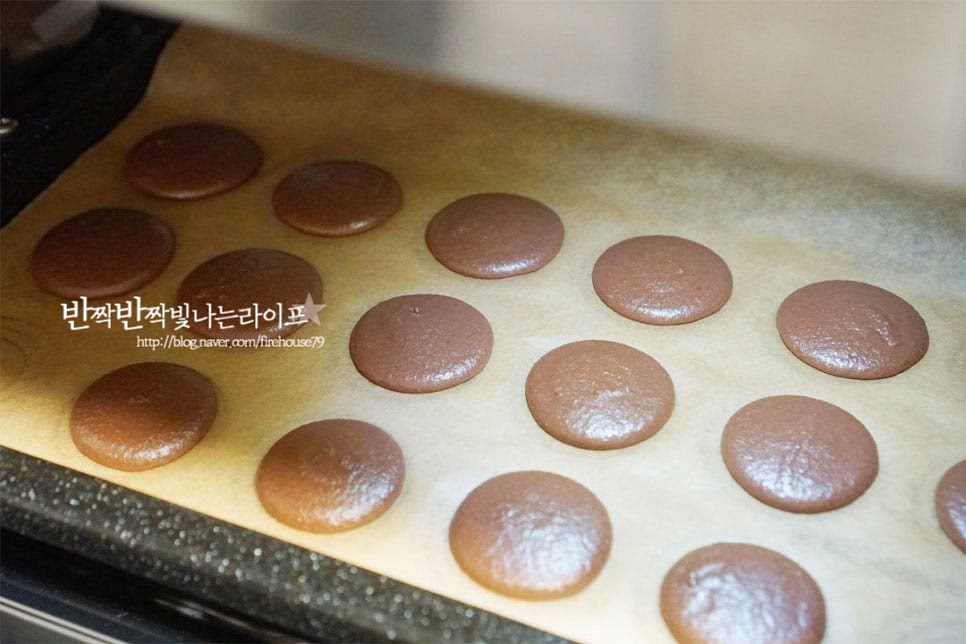 지름 1~1.2cm의 깍지를 끼운 짤주머니에 반죽을 담고 지름 4cm로 둥글게 짜줍니다. 수직으로 세워서 동그라미 가운데로 짜주어야 모양이 일정합니다. 그리고 팬 아래를 두드려 평평하게 정돈한 뒤 실온에 그대로 두고 건조해줍니다. 30분 이상 한 시간 정도 건조해 주면 되는데 습도에 따라 건조 시간의 차이는 있어요. 건조 후 손으로 만져보았을 때 손에 묻어나지 않으면서 약간 말랑한 느낌이 듭니다. 140도 예열한 오븐에 넣고 140도 15분 구워줍니다. 기기의 사양에 따라 온도와 시간을 조절해 주세요. 구워지면 팬을 식힌 뒤 떼어내어 줍니다. 잘 구워지면 구움색이 진하지 않고 부드러우며 팬에서 잘 분리가 됩니다.