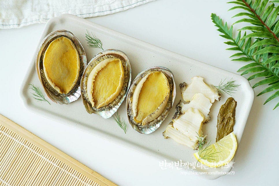 완성된 전복찜은 접시에 껍데기 위에 올려 먹음직스럽게 담아줍니다. 소스를 같이 담아내면 더 풍성해요. 뜨거울 때 먹으면 부드러우면서 쫀쫀하고 진한 바다감칠맛이 느껴집니다. 영상도 같이 담았어요. 회나 버터구이, 조림도 좋아하지만 재료 본연의 깊은 맛을 맛볼 수 있는 전복찜 만들기는 온 가족이 좋아하는 찜요리라 더운 여름에도 보양음식으로 챙겨먹곤 한답니다. 전복살을 얇게 저며 썰어서 내장으로 만든 고소한 게우소스에 찍어 먹음 녹진하게 맛볼 수 있고요. 전복찜 레시피로 맛있게 요리해드세요.