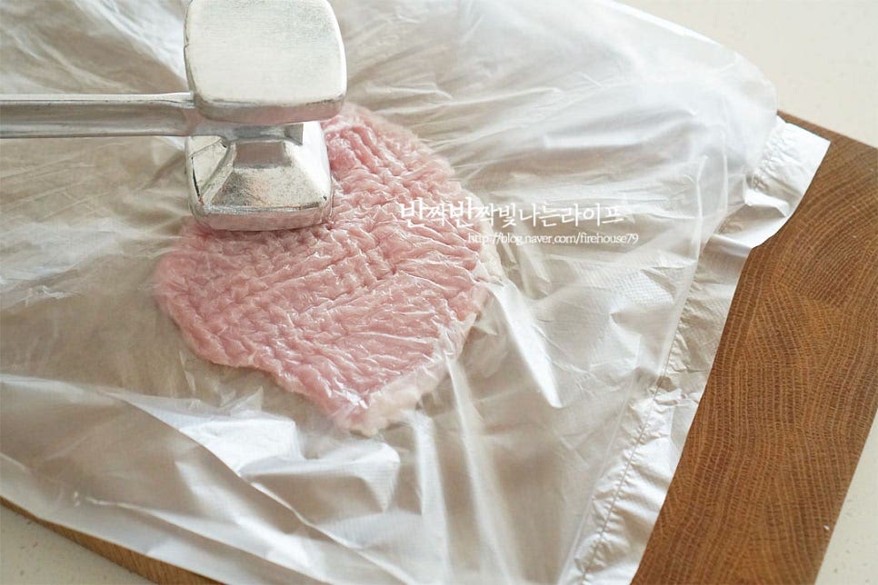 집에서 돈까스 만들기 위해 돼지고기 등심 600g을 준비했습니다. 보통 정육점에서 적당히 두툼하게 썰어서 한두 번 눌러주는데요. 경양식은 망치로 두들겨서 얇고 부드럽게 만듭니다. 비닐팩에 넣고 망치로 두드려서 얇게 펼쳐줍니다. 적당히 식감이 느껴지면서도 부드러워져요. 두툼하게 만든다면 칼집을 콕콕 찔러주세요. 하나씩 겹치지 않게 올려가며 소금, 후추 약간을 뿌려 5~10분 정도 밑간해요. 양파즙이나 간장으로 밑간하기도 하는데 신선한 돼지고기에 소금, 후추만 뿌려도 수제로 만든 고소한 맛을 느낄 수 있습니다.