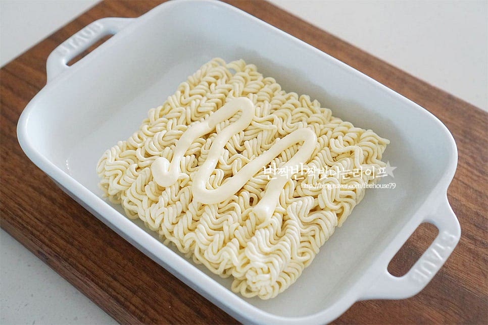 전자렌지 용기에 라면을 올리고 윗면에 마요네즈를 올려줍니다. 레시피에 적힌 기준은 마요네즈 3 큰 술인데요. 양쪽 면에 발라줄 것이라 1½ 큰 술 정도의 양을 먼저 올려줍니다. 칼로리는 걱정되지만 조금 넉넉하게 발라주셔야 더 맛있게 드실 수 있습니다. 주걱을 활용하여 고르게 펼쳐 발라줍니다.
