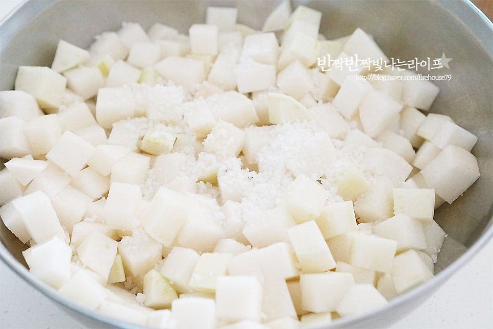 재료가 담길 정도의 큼직한 볼에 깍둑썬 무를 모두 넣어줍니다. 굵은소금 1½ 큰 술을 넣고 골고루 버무려 1시간 절입니다. 간수를 뺀 천일염을 사용했으며 무가 매운맛이 난다면 뉴슈가 1/2 작은 술을 함께 넣어주세요. 절이는 과정에서 무의 단맛을 살려주고 식감을 아삭하게 해줍니다.