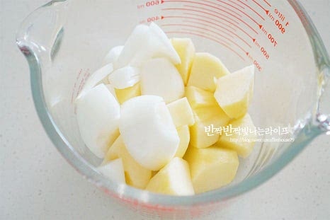 무가 절여지는 동안 양념을 준비하면 됩니다. 사과나 배, 양파와 같은 재료를 갈아서 넣으면 김치 양념에 은은한 단맛이 더해져 더욱 맛이 좋습니다. 먼저 사과 1/2개, 양파 1/4개를 큼직하게 썰어 넣고, 깐 마늘 12알, 생간 편 한 조각, 새우젓 1 큰 술 듬뿍, 액젓 2 큰 술, 매실액 2 큰 술을 넣어줍니다. 믹서기 또는 블렌더로 곱게 갈아줍니다. 간에 따라 액젓 1 큰 술 정도 추가해도 좋습니다. 준비한 고춧가루 5 큰 술 중 2 큰 술을 먼저 넣고 양념에 풀어지도록 섞어둡니다.