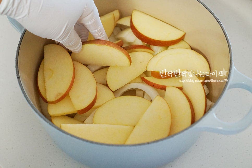 냄비에 양파와 사과를 먼저 깔아줍니다. 무수분 수육 삶기할 때는 바닥면이 두꺼운 냄비에 만들어주어야 눌어붙지 않고 열이 골고루 전달되면서 야채와 과일의 수분으로 익힐 수 있습니다. 그 위로 고기를 올려줍니다. 비계 부분이 위로 향하게 모양을 잡아줍니다. 사이로 대파, 마늘, 생강, 통후추, 월계수잎을 켜켜이 넣어줍니다. 향이 골고루 어우러지도록 사이사이 넣어주었어요. 생강술(청주) 100ml 부어줍니다.