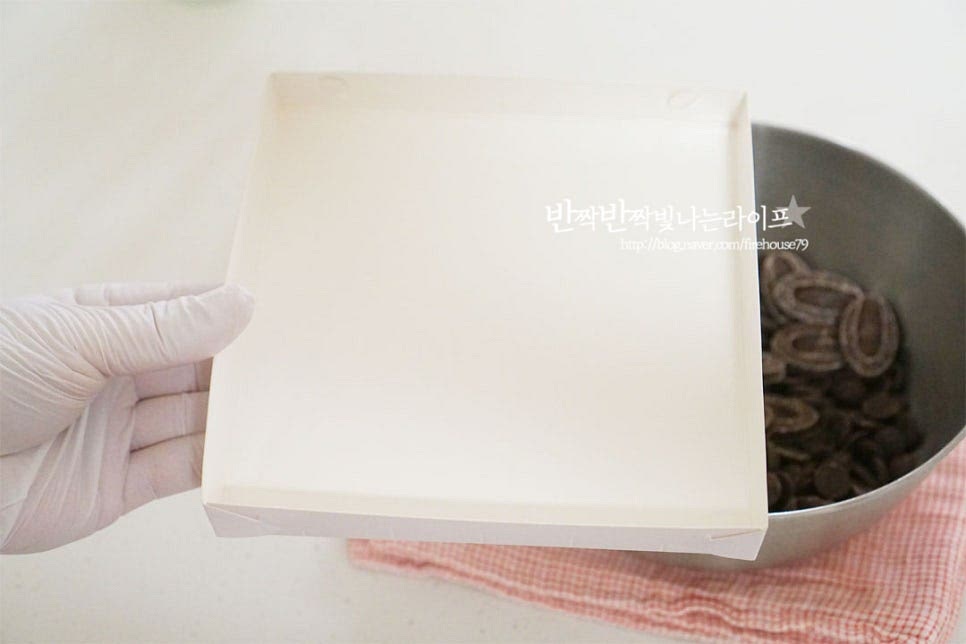 사방 15cm의 사각틀을 준비했습니다. 집에서 수제로 만들기 좋아 손쉽게 틀도 구입할 수 있는데요. 네모난 무스틀이나 사각용기를 활용해도 됩니다. 틀에 가나슈를 부어줍니다. 모서리 부분까지 골고루 펼쳐 담은 뒤 모양을 평평하게 해줍니다. 약간 고르지 않게 되어도 코코아가루를 뿌려줄 것이라 괜찮습니다. 열기를 식힌 뒤 냉장실에 넣고 두세 시간 굳혀줍니다.