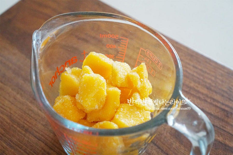 냉동 망고 다이스를 준비했어요. 얼린 상태로 갈아만들면 얼음을 넣지 않아도 시원하며 더욱 진한 과즙을 맛볼 수 있어요. 생과를 넣어 만드실 경우 얼음을 추가해 주시면 됩니다. 망고와 함께 플레인 요거트 150g을 넣어줍니다. 걸쭉한 액상 상태의 플레인 요거트를 넣으면 우유나 요거트파우더 없이 간단하게 만들 수 있는데요. 가당, 무가당 여부에 따라 단맛은 가감해 주시면 됩니다. 단맛을 더해주기 위해 꿀이나 설탕을 넣어주시면 됩니다. 당도에 따라 양을 더해주세요. 세 가지 재료를 넣고 그대로 갈아주면 된답니다^^