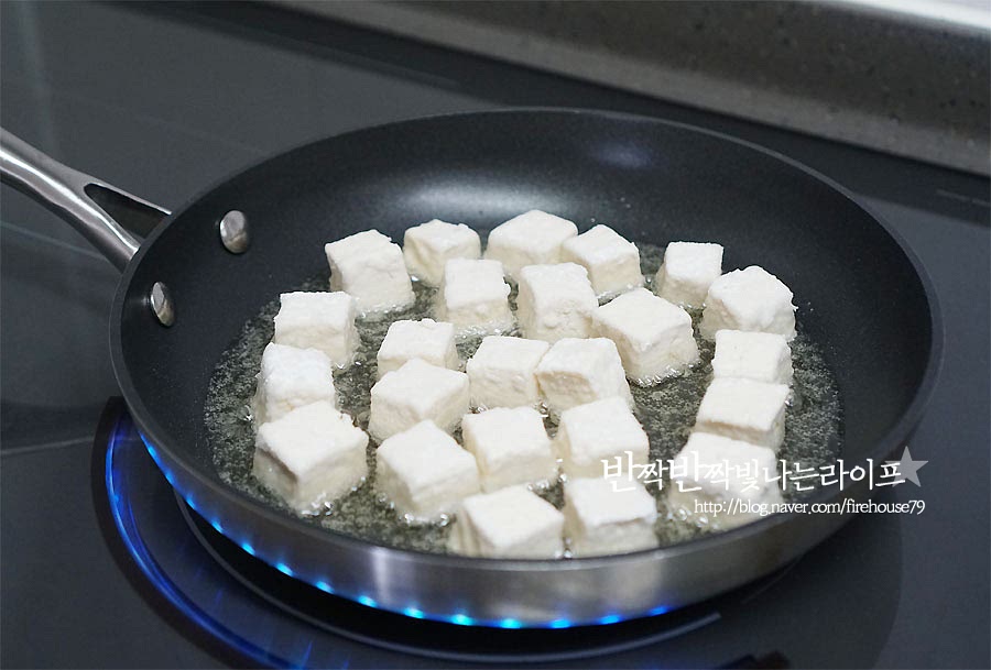 팬에 기름을 넉넉히 두르고 튀기듯이 익혀줍니다. 식용유를 재료가 완전히 잠길 정도로 넣을 필요 없이 자작하게 부어서 굴려가며 튀겨주면 조금 더 손쉽게 만들 수 있어요. 한 면 한 면 뒤집어가며 노릇하게 익혀주어요. 겉면이 고르게 구워져야 두부강정을 만들었을 때 내내 바삭바삭해요. 노릇하게 익으면 체에 밭쳐 기름을 빼줍니다. 하나 집어먹어보면 튀김옷이 바사삭한게 고소해서 이래로도 맛있어요.