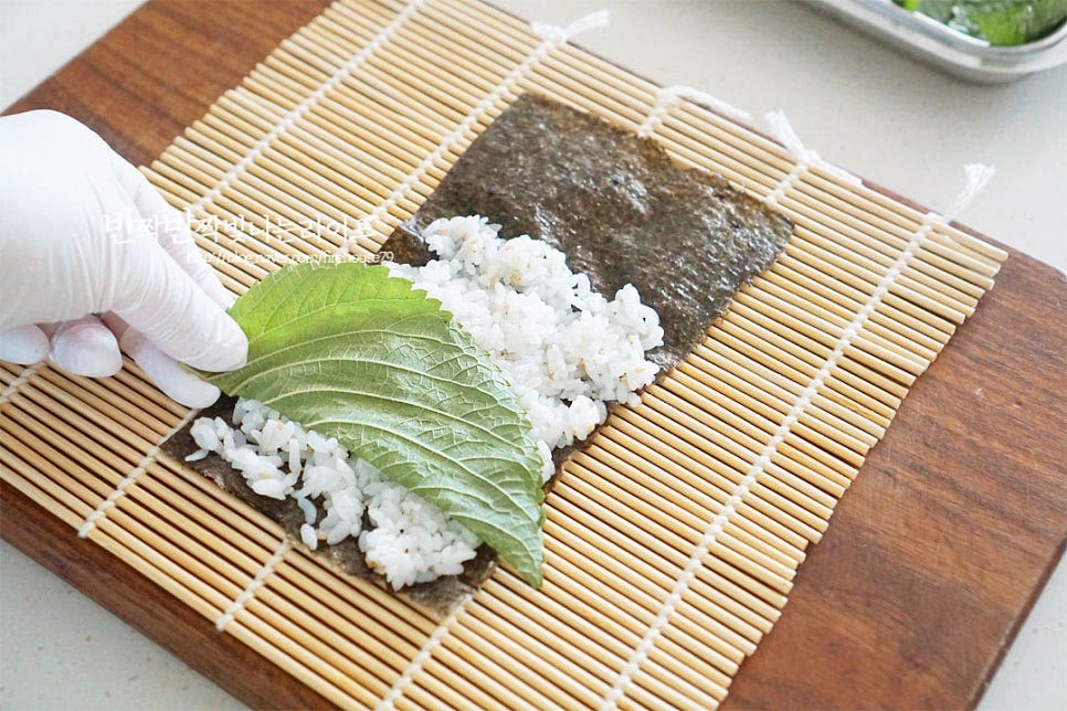 김발 위에 김을 올린 뒤 그 위로 밥을 넓게 펼쳐 올려줍니다. 즉석밥 한 공기 기준으로 4줄 넉넉하게 만들어져요. 밥의 양은 기호에 따라 적게 넣어도 됩니다. 깻잎 반장을 먼저 깔아주어요. 그 위로 계란지단, 단무지, 스팸을 올려요. 치즈를 넣을 땐 깻잎과 치즈를 먼저 깔아주면 되어요. 원형기둥처럼 돌돌 말아줍니다. 속이 꽉 차도록 힘을 주어 탄력 있게 말아주세요. 이렇게 8줄을 말아준 뒤 참기름 약간을 고르게 겉에 발라주면 고소한 풍미와 맛깔나게 윤기가 납니다~ 마무리는 참기름 발라주어야 터지지 않고 맛도 좋습니다. 그릇에 담아 통깨 솔솔 뿌려 줍니다. 고소한 윤기가 나면서 색감이 맛있어 보이는데요. 젓가락으로 집어 한입에 쏙 베어 물면 고소함, 짭조름함, 아삭함, 향긋함 여러 가지 맛이 어우러져 자꾸만 먹게 된답니다. 영상도 같이 담았어요. 여러가지 레시피 중에서도 간단하고 맛있게 스팸김밥 만들기 통조림햄의 짭조름함이 중심으로 맛과 식감이 풍부하답니다. 식감 있게 속을 큼직하게 채워주고, 김은 터지지 않게 반으로 잘라 말아주고, 참기름으로 마무리하면 간단 꼬마김밥싸는법 완성이에요. 스팸 꼬마김밥 만들기 맛있게 요리해 드세요^^ 끄읕 !