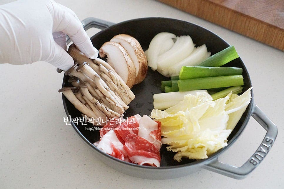 전골냄비에 준비한 재료를 담아줍니다. 다채롭게 맛볼 수 있도록 냄비를 따라 빙 둘러서 넣어주면 보기에도 먹음직스럽고 푸짐해요. 얇게 썬 소고기를 같이 넣어주면 끓일수록 구수한 맛이 깊어진답니다. 재료들과 어울려 익기 좋도록 얇게 썬 불고깃감이나 차돌박이, 샤브샤브용 고기를 준비해 주세요. 가운데로 만두를 올려줍니다. 향긋한 풍미를 위해 쑥갓 약간과 양념다대기, 고추를 올려 완성해요. 쑥갓이나 미나리 같은 향이 나는 채소가 들어가면 매콤 칼칼한 국물과도 잘 어울립니다. 푸짐하게 담은 뒤 식탁 위에 올려 뜨끈하게 바로 끓여서 먹으면 전골 요리를 더욱 풍성하고 맛있습니다. 여기에 칼국수나 수제비 같은 사리를 추가하고 먹고 난 뒤 볶음밥을 만들어도 좋고요. 김치만두가 들어가 매콤 칼칼한 감칠맛이 더해져 담백한 맛과 또 다른 별미랍니다.