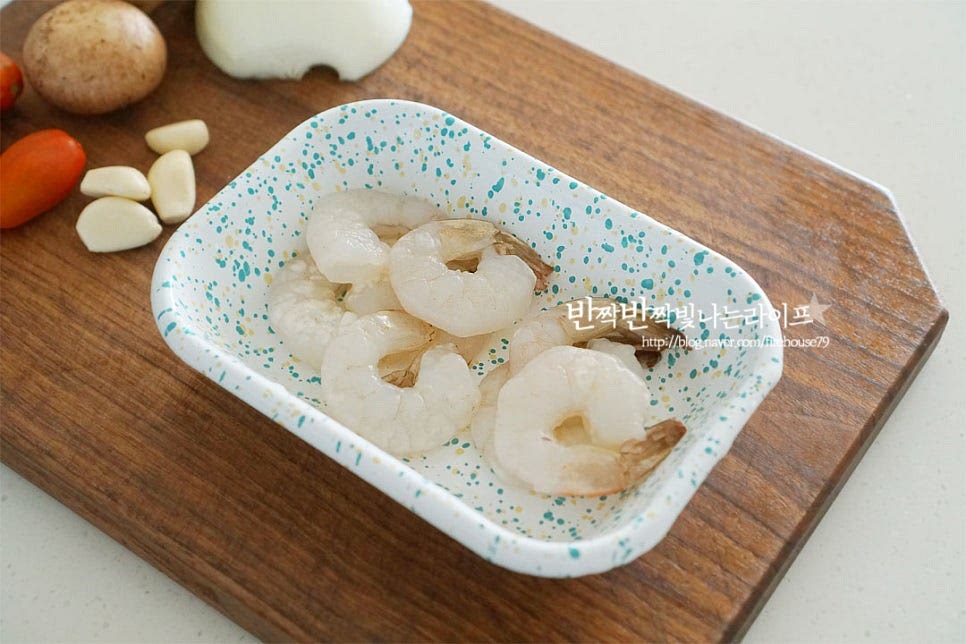 새우는 손질된 새우 살을 준비했어요. 해산물이나 육가공품은 취향껏 준비해 주세요. 마늘은 편으로 썰고, 양파는 잘게 썰어요. 양송이버섯은 슬라이스하고, 방울토마토는 꼭지를 제거하고 반으로 잘라줍니다. 토마토가 같이 들어가면 풍미가 더 좋아요. 베이컨은 2cm 정도의 너비로 채를 썰어 준비하여 줍니다.