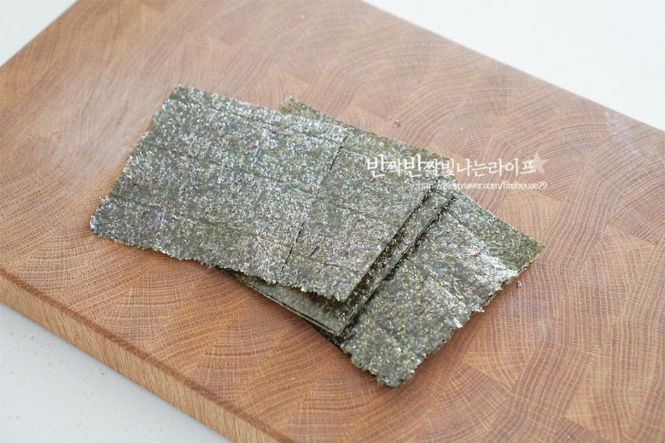 김은 4등분으로 잘라줍니다. 가위를 사용하여 간편하게 잘랐어요. 기본 속 재료 이외에 계란지단이나 당근, 햄과 같은 재료를 푸짐하게 넣는다면 김을 2등분으로 잘라 조금 크게 말아도 좋아요. 밥 한 공기를 볼에 담고 고소하게 양념해 줍니다. 김밥 밥은 그냥 먹어도 맛있게 밑간해주면 전체적으로 재료와 간이 잘 맞습니다. 참기름 1½ 큰 술, 빻은 깨 2/3 큰 술 고운 소금 1/4 작은 술 넣어줍니다. 맛소금도 좋습니다. 통깨보다 빻은 깨 넣으면 더 고소합니다. 양념이 뭉치지 않게 잘 섞어줍니다.