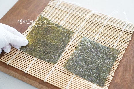 김을 먼저 올려준 뒤 밥을 넓게 펼쳐 올려줍니다. 뭉치지 않게 얇게 올려주면 속 재료의 맛을 더 고소하게 맛볼 수 있습니다. 그 위로 깻잎을 올려줍니다. 매끈한 앞면이 밥쪽으로 향하게 놓으면 말았을 때 맛있어 보입니다. 단무지와 참치 마요를 올려줍니다. 4등분 한 김이기 때문에 속을 적당하게 넣어야 먹기좋게 말아집니다. 깻잎 양끝으로 감싸줍니다. 끝부분을 밥끝과 맞닿도록 동그랗게 말아서 돌돌 말아줍니다. 같은 조리방법으로 말아줍니다. 말아준 뒤 참기름을 골고루 발라줍니다. 윤기나서 맛있어 보이고 고소해요.