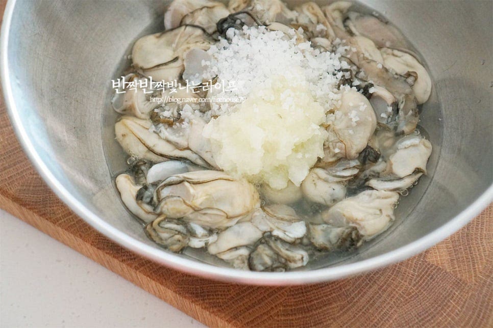 굴은 만져보았을 때 탄력이 있으며 검은태가 뚜렷한 것이 싱싱해요. 잘못 먹으면 탈이 날 수 있으니 신선한 것으로 무침이나 젓갈을 만들고, 아니라면 익혀드시는 게 좋습니다. 수산시장에서 껍질을 벗겨 손질된 것을 사 왔는데요. 가볍게 세척이 되었지만 요리하기에 앞서 손질을 해줍니다. 넉넉한 크기의 볼에 담고 굵은소금 1 큰 술, 간 무 3 큰 술을 넣어줍니다. 소금으로만 간단하게 세척해 주어도 되지만 굴무생채 무침에 무가 들어가기 때문에 조금 잘라내어 갈아서 넣어주었습니다. 무즙으로 씻어주면 불순물을 흡수 제거하여 손질하기에 좋습니다. 소금을 물에 희석해도 되지만 무즙을 넣어줄 것이라 그대로 넣고 숟가락으로 살살 저어주었어요. 젓다보면 불순물이 보이는데요. 터지지 않도록 물을 부어 살살 저어 두세 번 이상 헹구어 줍니다. 맹물에 오래 담그거나 많이 씻게 되면 되려 맛있는 향이 사라져 싱거울 수 있습니다. 행군 뒤 체에 밭쳐 물기를 털어줍니다.