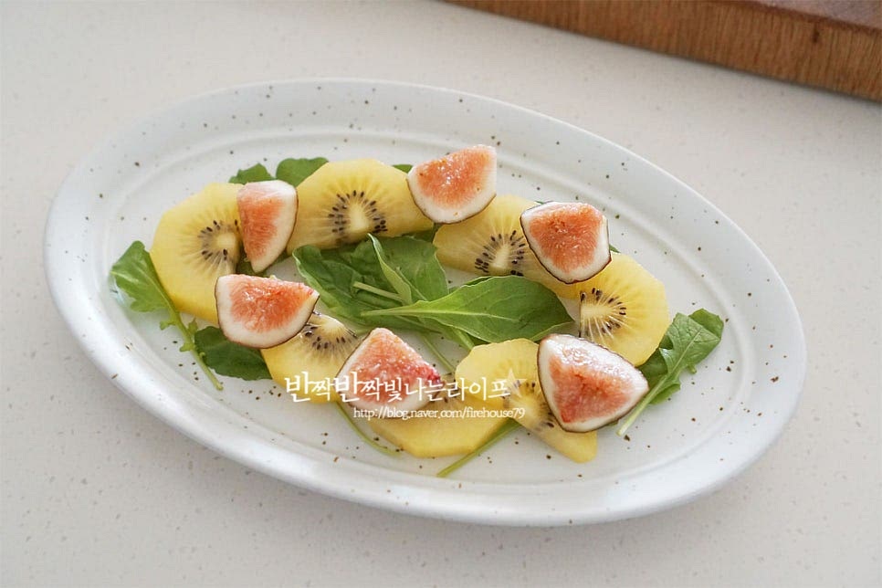 준비한 접시에 루꼴라를 먼저 올리고 그 위로 재료가 돋보일 수 있도록 키위와 무화과를 올려줍니다. 가운데로 브라타치즈를 올려줍니다. 치즈를 미리 꺼내두어서 먹기 딱 좋습니다. 만들어둔 소스를 뿌려 부라타치즈 샐러드를 완성합니다.