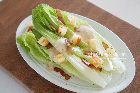 로메인 상추를 먼저 올린 뒤 드레싱 소스를 뿌려주고, 크루통과 베이컨, 치즈를 갈아 곁들여 줍니다. 시저샐러드는 야채와 크루통, 베이컨, 치즈를 기본으로 토핑을 곁들여 먹음 푸짐하게 맛볼 수 있는데요. 든든하게 삶은 계란을 잘라 곁들였는데 구운 닭이나 스테이크 생선구이, 아보카도, 토마토 등 여러 가지 재료를 더해주면 맛깔납니다. 식감과 맛이 풍부한 로메인샐러드로 직접 수제로 만든 드레싱이 맛있게 잘 어울린답니다. 곁들이는 재료들이 어우러진 푸짐함과 맛이 별미에요. 먹기 전 바로 담아 완성해 주셔야 눅눅해지지 않고 바삭하고 아삭하게 맛볼 수 있습니다. 영상도 같이 담았어요. 로메인상추와 크루통, 베이컨에 더해진 짭조름하고 산뜻한 소스 레시피는 한번 먹으면 계속 먹고 싶어지는 맛이에요. 시저샐러드 드레싱을 곁들여 맛있게 만드는법 아삭한 식감과 감칠맛 풍부하게 즐겨보세요. 끄읕 !