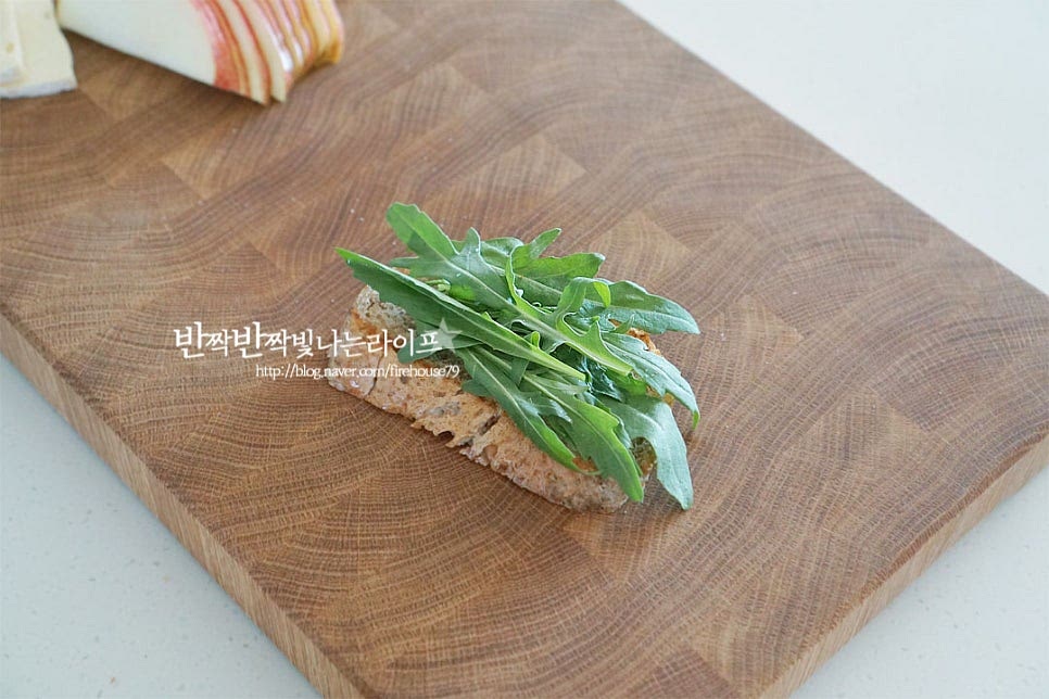 구운 통밀빵 위에 루꼴라를 올려줍니다. 쌉싸래한 루꼴라의 향이 사과브리치즈와 잘 어울리는데 연한 잎채소를 올려주어도 좋습니다. 그 위로 브리와 사과를 올려줍니다. 길이에 맞추어 먹음직스럽게 모양을 내어주세요. 고소한 견과를 올려주면 먹음직스럽기도 하고 고소해서 더 맛이 좋아요. 오독오독 식감을 위해 큼직하게 다져썰어줍니다. 견과를 올려준 뒤 꿀을 약간 뿌려줍니다. 아가베 시럽이나 메이플시럽도 좋아요. 달콤함이 더해져 재료의 맛이 풍성해진답니다. 과일을 올린 오픈샌드위치는 다른 레시피 중에서도 간단하면서 근사한데요. 속재료를 풍성하고 먹음직스럽게 올려주면 완성이랍니다. 영상도 같이 담았어요. 바삭바삭한 빵 위로 진한 부드러움과 아삭한 달콤함, 고소하고 쌉싸래하면서 은은한 단맛의 여러 가지가 어우러져 더욱 빛이 나는 맛이랍니다. 사과 듬뿍 올린 브리치즈 샌드위치 레시피로 맛있는 별미를 즐겨보세요^^ 끄읕 !