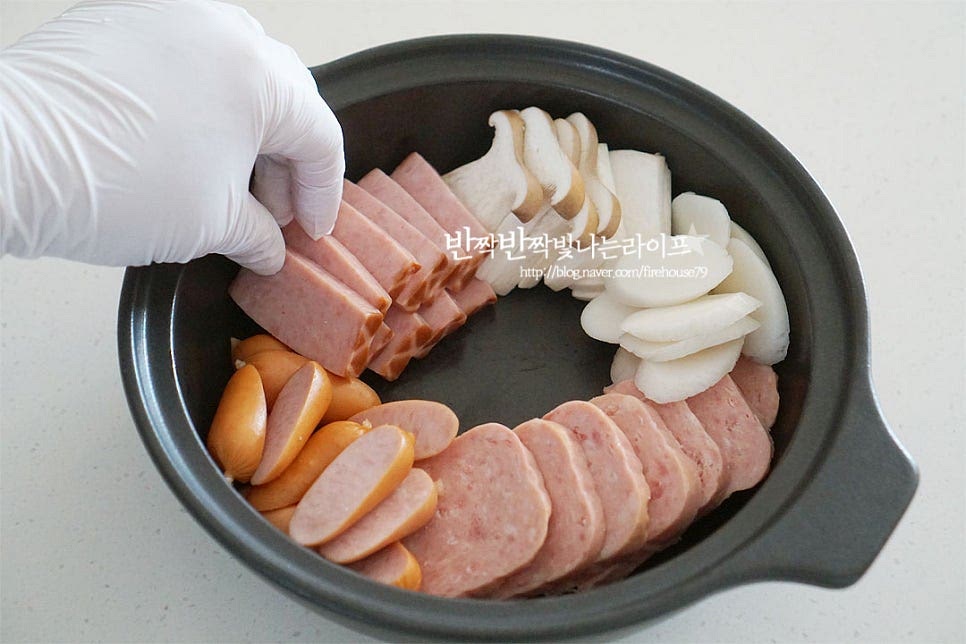 넓은 전골냄비에 준비한 재료를 담아줍니다. 햄과 버섯, 떡국떡을 넣어줍니다. 가운데 양파를 담고 그 위로 김치와 다진 돼지고기, 베이크드빈스, 대파를 넣어줍니다. 빠질 수 없는 부대찌개 레시피의 필수 베이크드빈스가 들어가면 특유의 맛을 더 살려준답니다~ 양념장 2/3 정도 넣어줍니다. 김치와 햄에서 짠맛이 우러나기 때문에 절반 정도의 양념을 먼저 넣고 라면사리와 추가로 더 넣어주었습니다. 사골육수+물을 부어줍니다. 냄비에 모두 넣은 뒤 그대로 식탁 위에 올려 즉석으로 끓여드시면 밖에서 먹는 맛 못지않게 맛보실 수 있어요. 홍고추와 체더치즈, 쑥갓도 같이 올려주었습니다. 저는 아이랑 먹을 것이라 안전상 인덕션에서 먼저 끓인 뒤 식탁 위에 올려 먹었어요. 충분히 끓여주면 냄비 안에서 어우러지는 재료들의 맛이 깊고 진해져요. 라면사리도 같이 넣고 끓여주었어요. 영상도 같이 담았어요. 김치 부대찌개가 보글보글 끓으면 푸짐하게 담긴 햄과 소시지, 채소와 버섯 양념장과 재료가 익어가며 매콤 칼칼하면서 진한 고소함이 가득해요. 면이나 떡사리를 함께 즐기는 맛도 좋으니 냉장고 속 재료를 다양하게 넣어 만드시면 맛나요. 부대찌개 황금레시피 맛있게 만들어 드세요^^ 끄읕 !