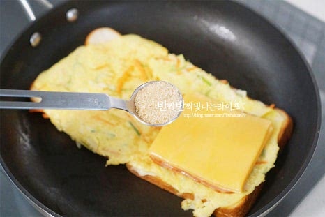 길거리에서 사 먹던 토스트는 달콤하게 설탕이 뿌려진 맛이죠. 설탕 1 작은 술 정도를 골고루 뿌려줍니다. 단맛은 입맛에 맞게 조절해 주고, 딸기잼을 발라도 좋습니다. 적당량의 단맛이 케첩의 새콤달콤한 풍미를 더 풍성하게 더해준답니다. 케첩도 골고루 뿌려줍니다. 기본적인 소스만으로도 맛있죠. 케요네즈소스를 뿌려도 좋아요. 펼쳐진 두 개의 빵 중 하나를 반으로 접어 완성합니다. 이렇게 만들면 원팬으로 간단하게 토스트를 만들 수 있어요.