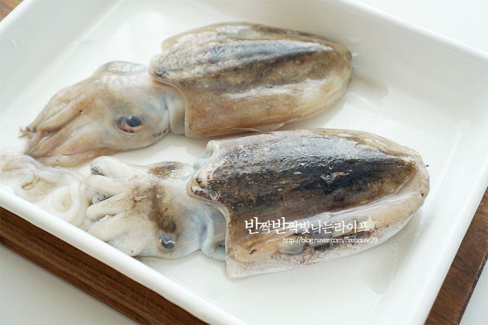 갑오징어 손질을 시작해요. 손으로 만져보았을 때 살이 단단하고 탄력 있는 게 신선한 것인데요. 등면에 뼈가 있기 때문에 그 부분을 유의하여 손질하여 주면 되어요~ 먼저 몸통을 가른 뒤 내장을 제거하여 주는데요. 가위나 칼을 이용하여 눈 윗부분 쪽 몸통을 갈라주어요. 먹물이 터지지 않게 옆부분 쪽으로 갈라내어 줍니다. 안으로 먹물과 내장이 보여요. 이 부분을 제거하여 줍니다. 진액이 묻어나기 때문에 흐르는 물과 함께 갑오징어손질 하여주면 보다 손쉽게 할 수 있습니다^^ 내장을 제거하다 보면 자연스럽게 사이에 들어있는 연골조직이 분리되어요. 이 부분 역시 제거하여 줍니다. 끝부분 껍질을 잡아당기면 껍질도 스윽 벗겨진답니다~ 분리한 다리 부분에 있는 눈과 입도 제거해 줍니다. 손으로 쉽게 분리되는 편인데 분리가 잘되지 않는다면 가위를 사용하여 잘라내어 줍니다. 먹기 좋게 손질하여 주면 하얀 살점이 깨끗해요.