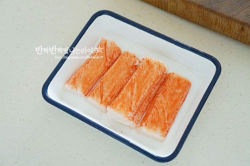 크래미는 100g 정도를 준비한 뒤 겉껍질을 모두 제거합니다. 결대로 먹기 좋게 찢어줍니다. 결이 난 방향이 있어 손질하게 편합니다. 오이는 굵은소금으로 문질러 세척한 뒤 껍질을 돌려 깎아줍니다. 물이 생기지 않도록 가운데 씨를 제거하고 겉 부분을 얇게 돌려 깎았습니다. 크래미 결식감과 어우러지도록 길이와 두께를 맞추어 채 썰어줍니다. 아삭아삭 오이가 산뜻하게 식감을 더해줍니다. 넉넉한 크기의 볼에 손질한 크래미와 오이를 담아줍니다. 마요네즈만 넣고 바로 버무려먹어도 맛있지만 양념재료를 더해줍니다. 마요네즈 1½~2 큰 술, 허니 머스터드 1/2 큰 술, 고추냉이 1/2 작은 술, 소금과 후추 약간 넣어줍니다. 간에 따라 허니머스타드 대신 설탕이나 알룰로스 약간 더해 단맛 감칠맛을 더해도 좋으며 알싸하게 매운맛 입맛에 따라 고추냉이는 조절해줍니다. 고추냉이가 약간 들어가면 매운맛보다 개운합니다. 뭉치지 않게 재료를 잘 버무려줍니다.