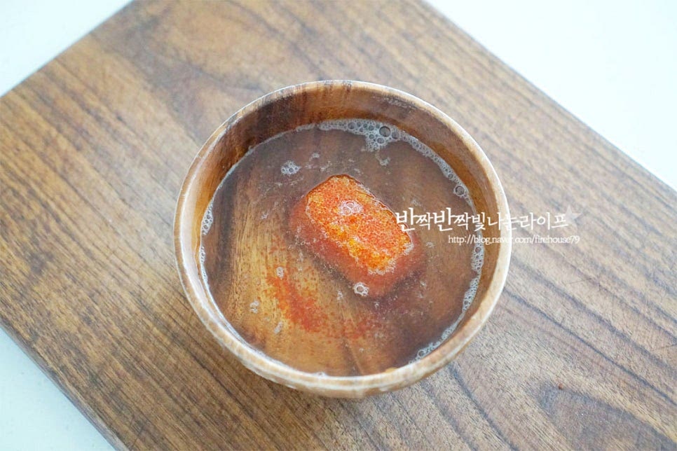 날치알요리를 만들 때 날치알 비린내를 잡아 해동해 주시면 되는데요. 보통 냉동상태로 소분되어 판매되기 때문에 냉동실에서 꺼내어 해동해줍니다. 그릇에 잠길 정도의 찬물을 붓고 청주 또는 맛술 1 큰 술 넣어줍니다. 체에 밭쳐 알코올이 날아가도록 가볍게 흔들어 씻어준 뒤 물기를 털어줍니다.