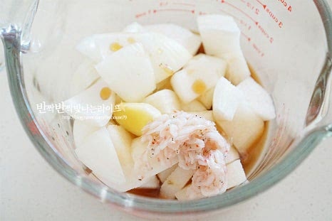 무가 절여지는 동안 양념을 만들어줍니다. 믹서기나 블렌더로 갈아주는 재료를 먼저 준비합니다. 갈아줄 재료로 배 1/4개, 양파 1/4개, 생강 마늘 한 알 크기, 새우젓 (건더기) 1 큰 술, 액젓 4 큰 술을 넣어줍니다. 간 마늘이 아닌 통마늘을 준비했다면 같이 넣어주면 됩니다. 블렌더로 곱게 갈아준 뒤 고춧가루 1컵, 간 마늘 2 큰 술, 매실액 2 큰 술, 찹쌀 풀을 넣고 잘 섞어줍니다. 배와 매실액으로 은은한 단맛을 내어주는데 간에 따라 설탕 1 큰 술 정도 넣어주셔도 좋습니다. 고춧가루가 풀어지면서 총각김치 양념이 매콤한 감칠맛나게 어우러집니다. 간에 따라 액젓과 새우젓은 조절해줍니다.