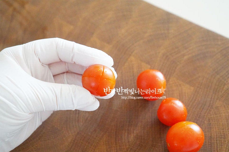 겉의 껍질을 벗긴 뒤 과육에 발사믹 소스가 절여질 수 있도록 해주기 위해 껍질을 제거해 줍니다. 열십자로 칼집을 넣어줍니다. 겉껍질에만 칼집을 넣어야 속의 과즙이 새어나지 않습니다. 칼집을 모두 넣어주었습니다. 냄비에 물 500ml를 붓고 팔팔 끓어오르면 토마토를 넣어줍니다. 뜨거운 물에 살짝만 데쳐주어도 껍질이 쉽게 벗겨지기 때문에 20~30초 넣었다가 바로 건져내어줍니다. 오래 데치면 절였을 때 식감이 물러질 수 있어요. 뜨거울 때 바로 찬물 또는 얼음물에 담그면 손쉽게 껍질을 제거할 수 있습니다. 칼집을 넣은 부분으로 슥 쉽게 벗겨집니다.