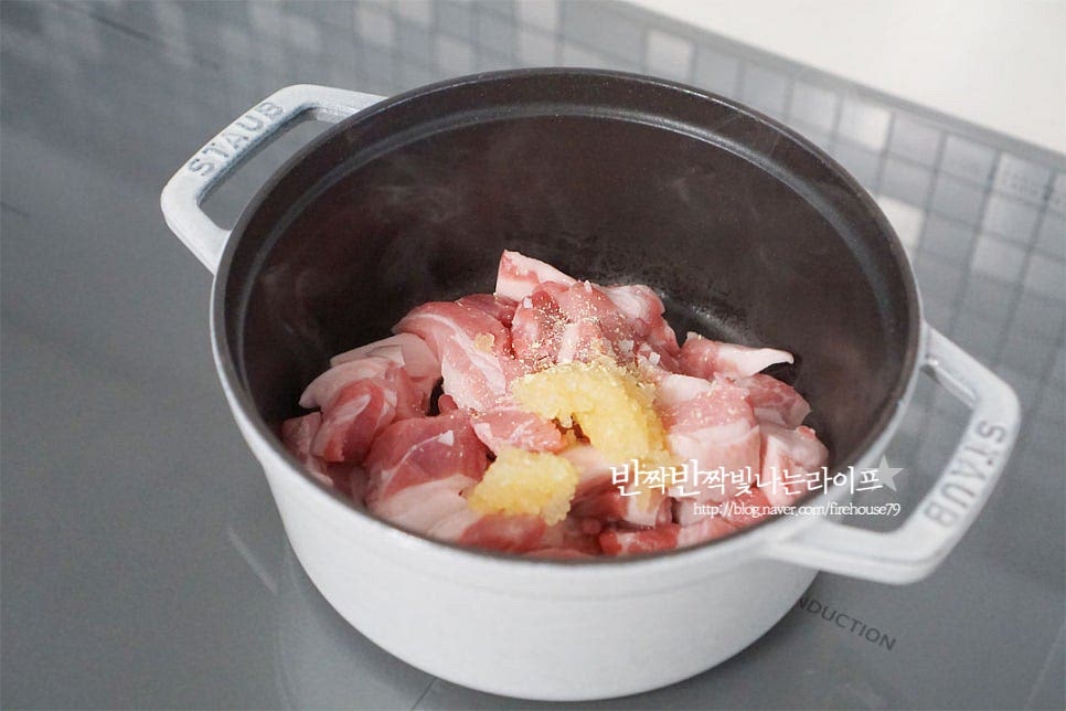 달군 팬에 식용유 1 큰 술을 두르고 소금, 후추 약간, 다진 마늘 1/2 큰 술 생강가루 약간 넣고 돼지고기를 볶아줍니다. 짜지 않게 소금을 약간 뿌려주면 간이 더 맛있게 스며들어요. 겉면을 익혀가며 볶아줍니다. 먼저 볶아서 익혀주면 돼지비계에서 나오는 고소한 풍미도 살리고 누린내 없이 찌개의 맛을 낼 수 있어요. 겉이 익으면 썰어둔 김치를 넣어줍니다. 묵은지 김치찌개 팁~ 신맛 정도에 따라 설탕을 약간 넣어주면 새콤한 맛을 잡아줄 수 있어요. 황설탕 1 작은 술 넣어주었습니다. 김칫소를 덜어내어 깔끔하게 맛을 내어주고, 몇 가지 양념재료로 감칠맛을 살려줍니다. 고춧가루 1½ 큰 술을 넣고 달달 볶아줍니다. 충분하게 볶아주면 더 깊은 국물맛과 고춧가루가 풀어지면서 색도 맛깔나게 끓일 수 있어요.