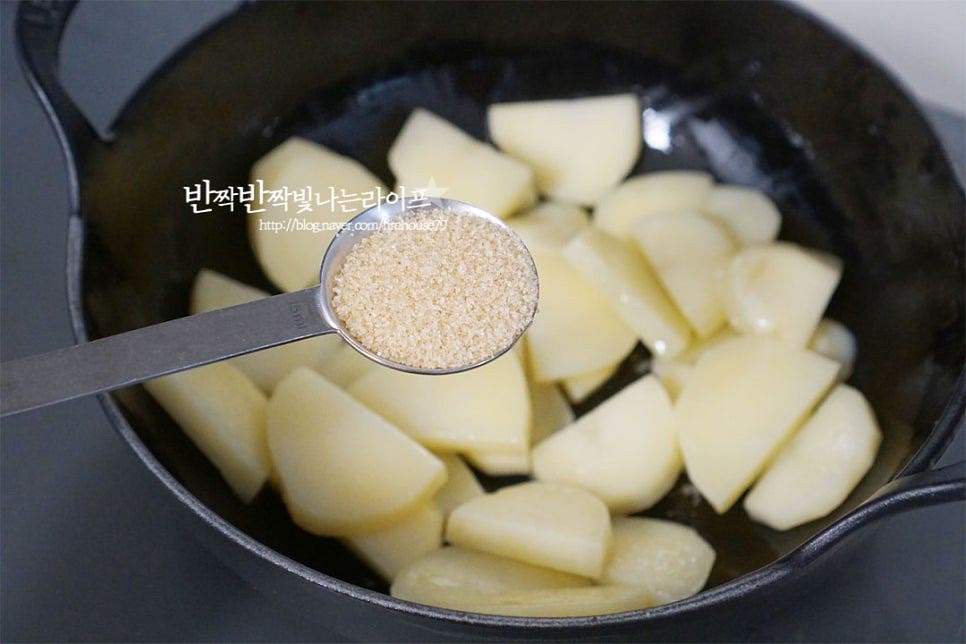 달군 팬에 식용유 1½ 큰 술을 두르고 감자를 먼저 볶아줍니다. 볶은 뒤 조려주면 부서지지 않게 만들 수 있어요. 전체적으로 기름이 코팅되도록 2분 정도 볶다가 황설탕 1 큰 술을 넣어줍니다. 설탕 입자가 굵기 때문에 볶아서 단맛이 어우러지도록 한 뒤 나머지 양념을 넣어줄 것이에요. 설탕이 녹아 볶아지도록 해줍니다. 단맛이 배고 겉이 투명빛이 돌아요.