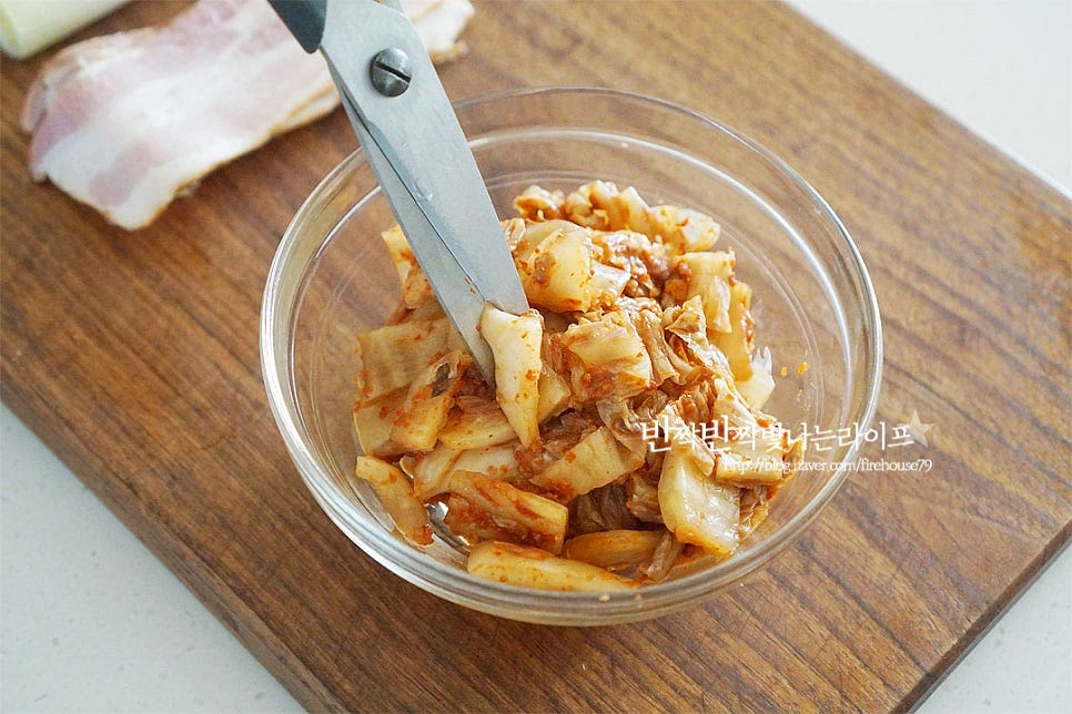 가장 핵심적인 재료인 김치는 잘 숙성된 신 김치로 준비해 줍니다. 간편하게 가위를 사용하여 먹기 좋게 잘게 잘라줍니다. 가위로 잘라주시면 도마에 김치 국물이 묻지 않아 자르기도 편하고 정리도 간편해요. 베이컨도 김치와 밸런스를 맞추어 채를 썰어 준비해 주시고, 대파 흰 부분은 반으로 갈라 송송 썰어줍니다. 보관용 고기로 소시지, 통조림햄 등 냉장고 사정에 따라 넣어주셔도 좋아요.